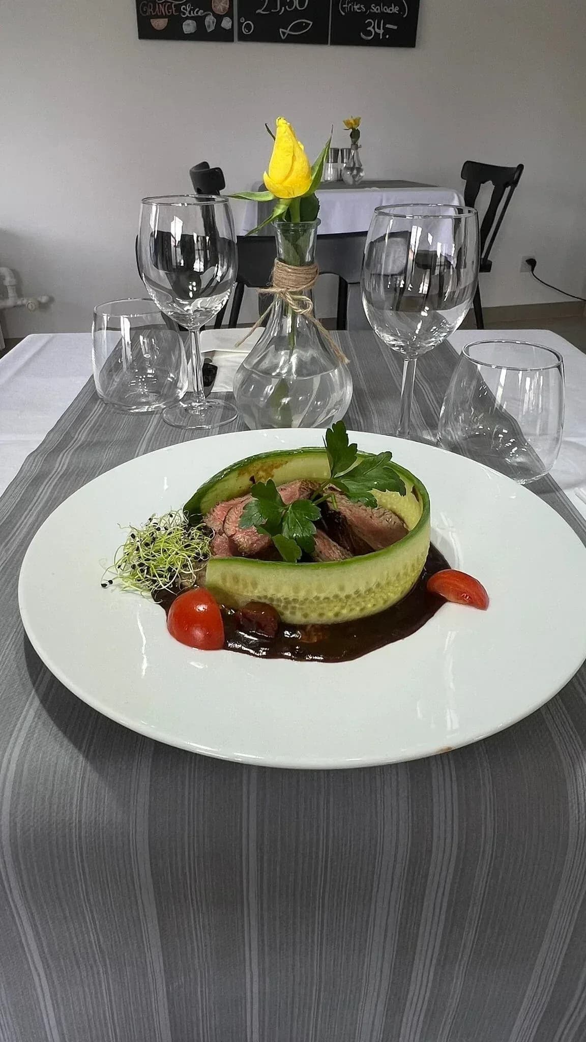 Pièce de bœuf tranchée dans un ruban de concombre, sauce brune et pousses