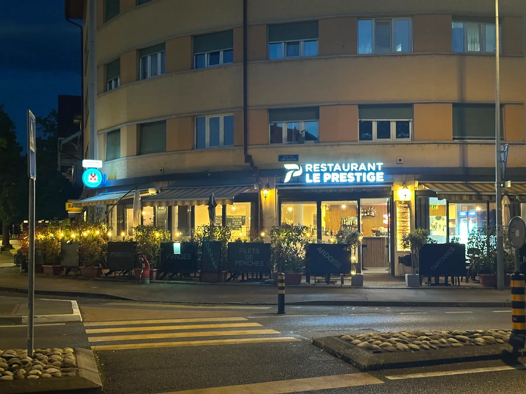 La façade du Prestige de nuit, vue depuis le passage piéton, enseigne allumée