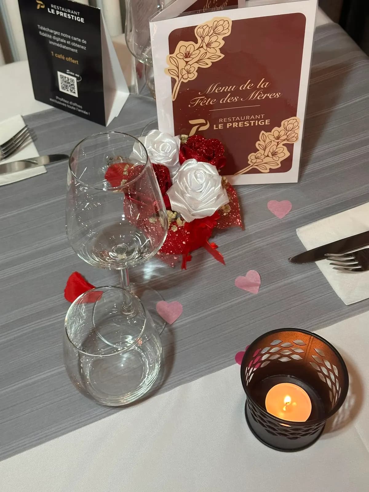 Une table dressée pour une occasion, bougie et pétales rouges
