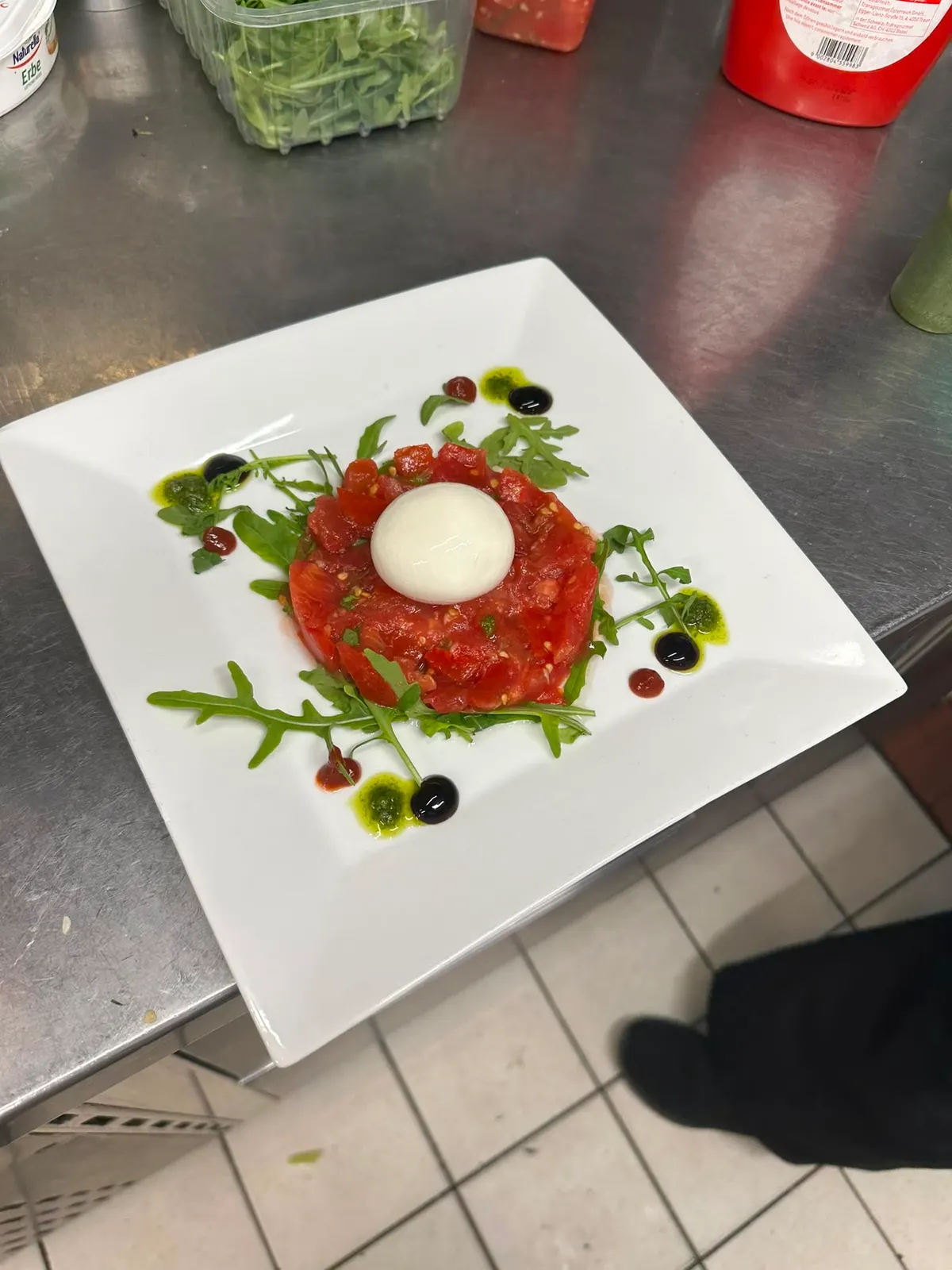 Un tartare monté rond, jaune d'œuf au centre, sur assiette carrée blanche