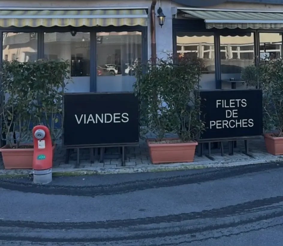 La devanture du restaurant, deux panneaux peints « Viandes » et « Filets de perches » devant les fenêtres